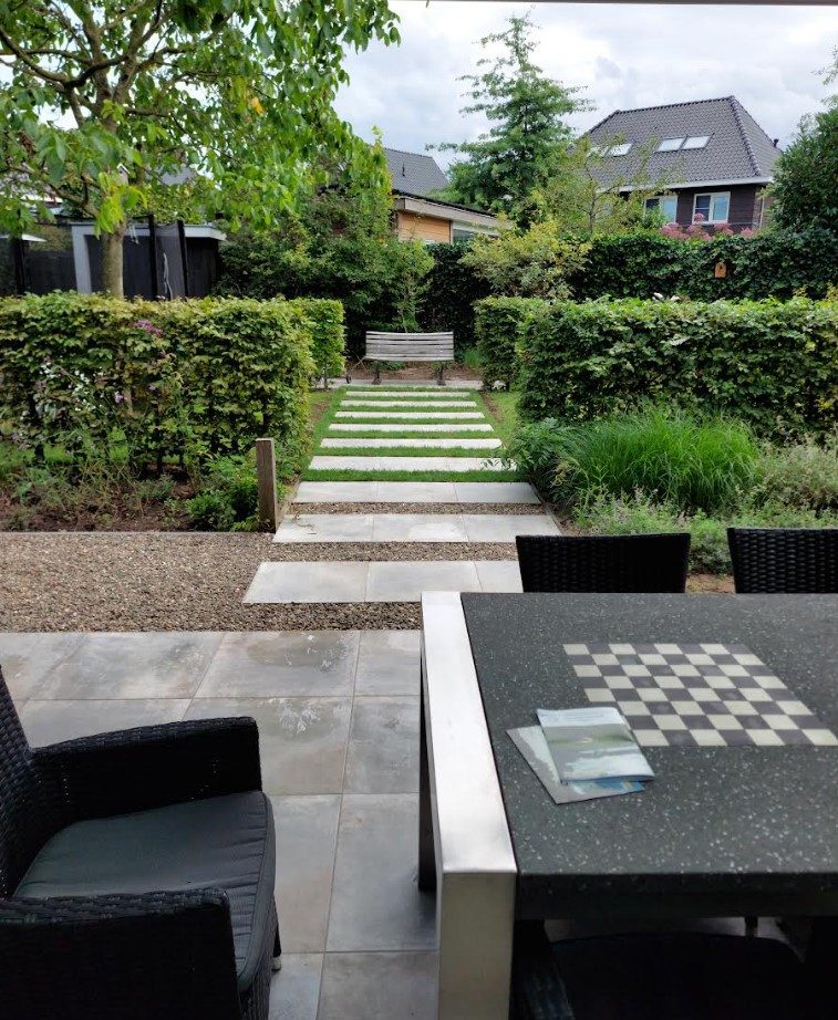 Strakke tuin met stapstenen pad, hagen en eettafel