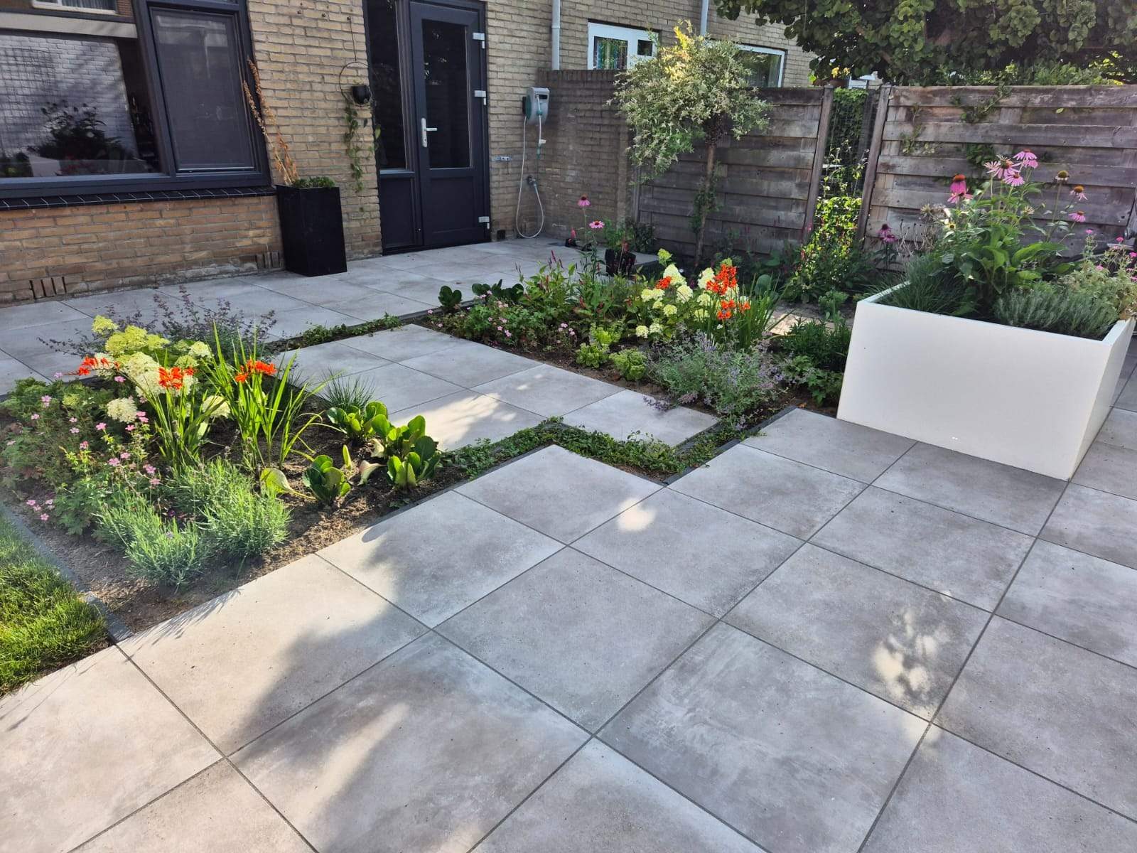 Aangelegde voortuin met bestrating, stapstenen en beplanting